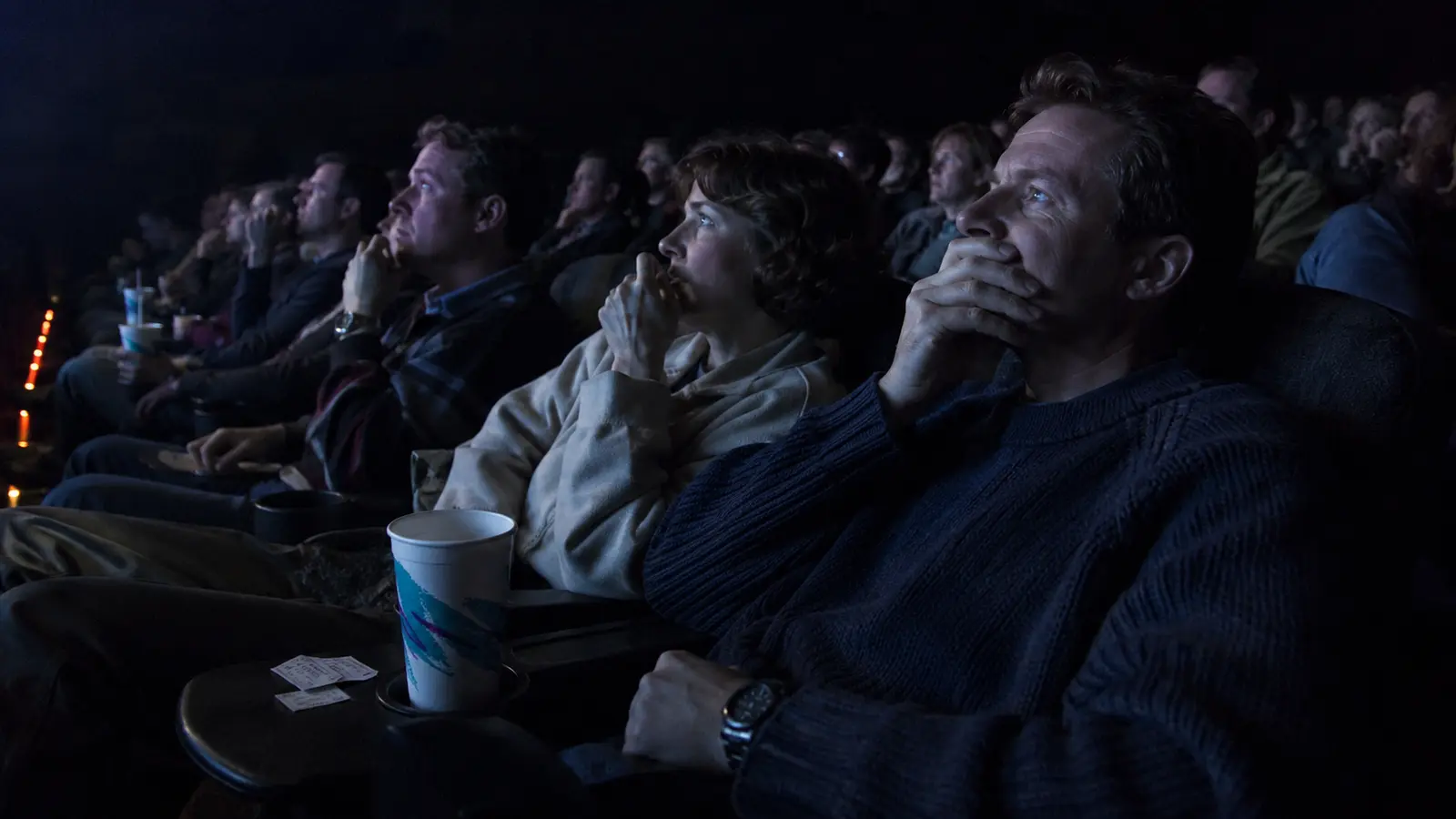 Espectadores de las películas más taquilleras de 1997 reaccionan durante una función iluminada por la pantalla.