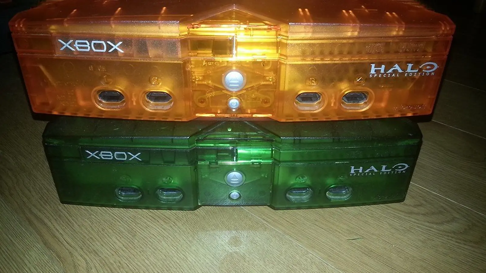 Dos consolas Xbox originales translúcidas de edición Halo, una naranja y otra verde