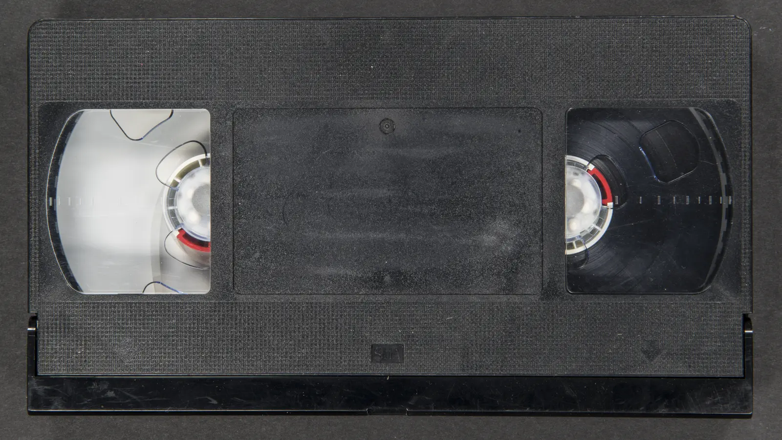 Cinta VHS negra fotografiada sobre una superficie clara.