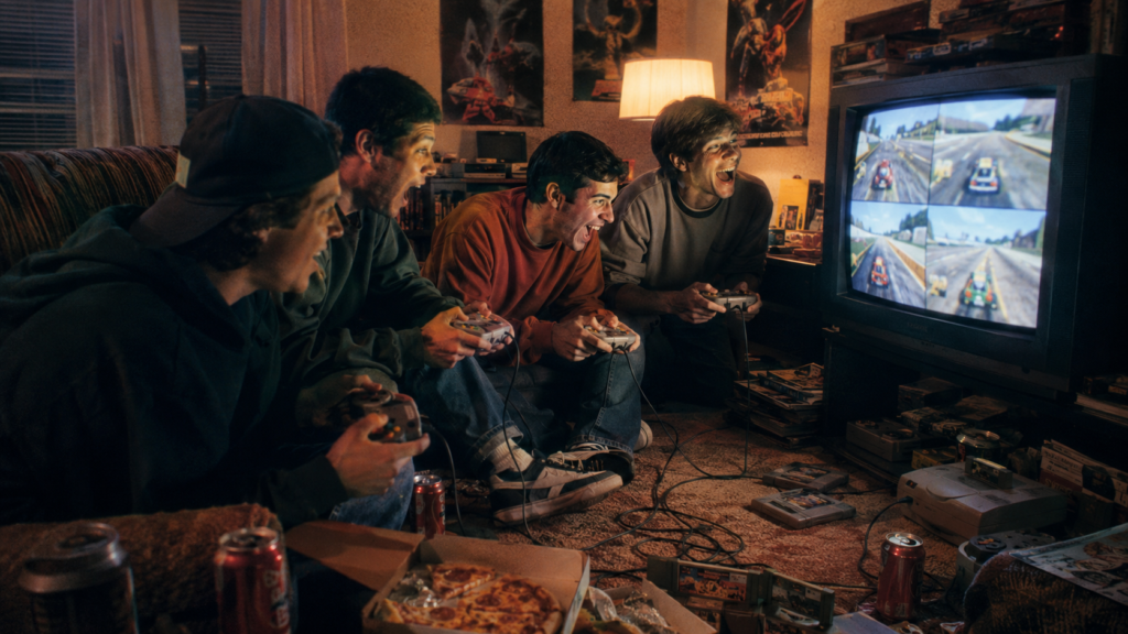Cuatro amigos jugando en pantalla dividida en una televisión CRT durante una noche multijugador de los años 90