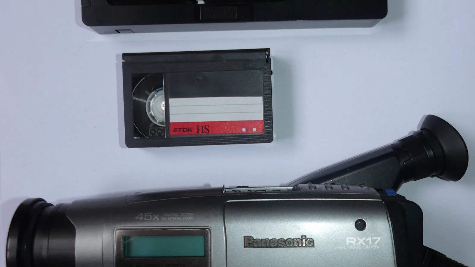 Videocámara Panasonic VHS-C junto a un casete compacto sobre una mesa clara.