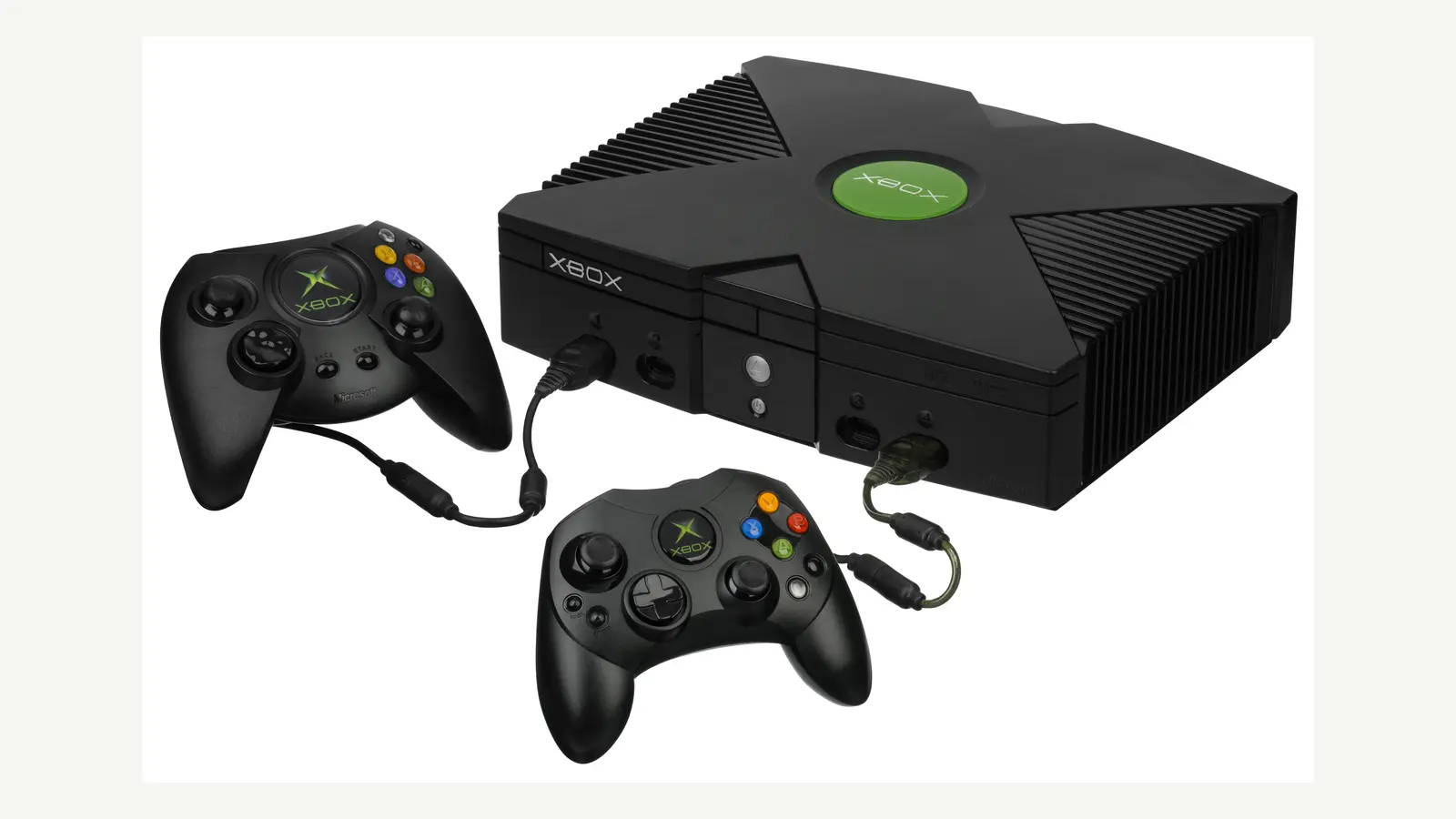 Consola Xbox original negra junto a los controles Duke y S sobre un fondo claro