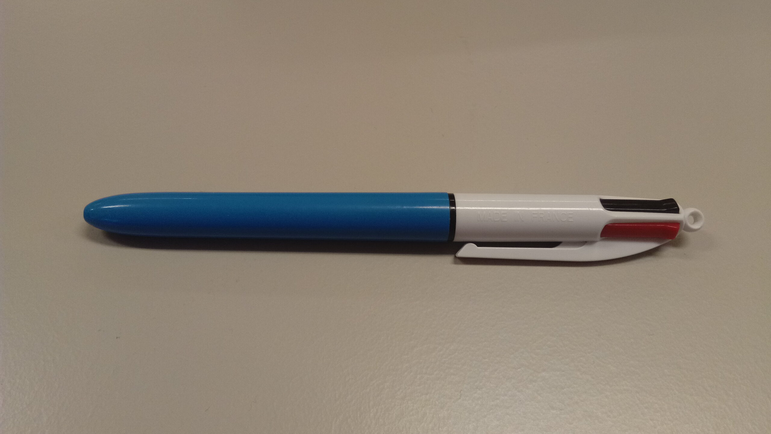 Bolígrafo BIC de cuatro colores con cuerpo azul y blanco sobre una mesa