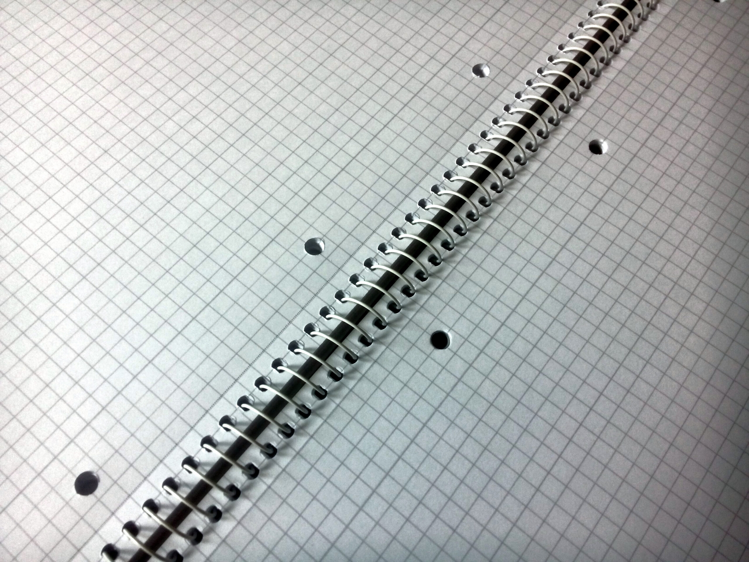 Detalle en diagonal de un cuaderno cuadriculado abierto con encuadernación de espiral
